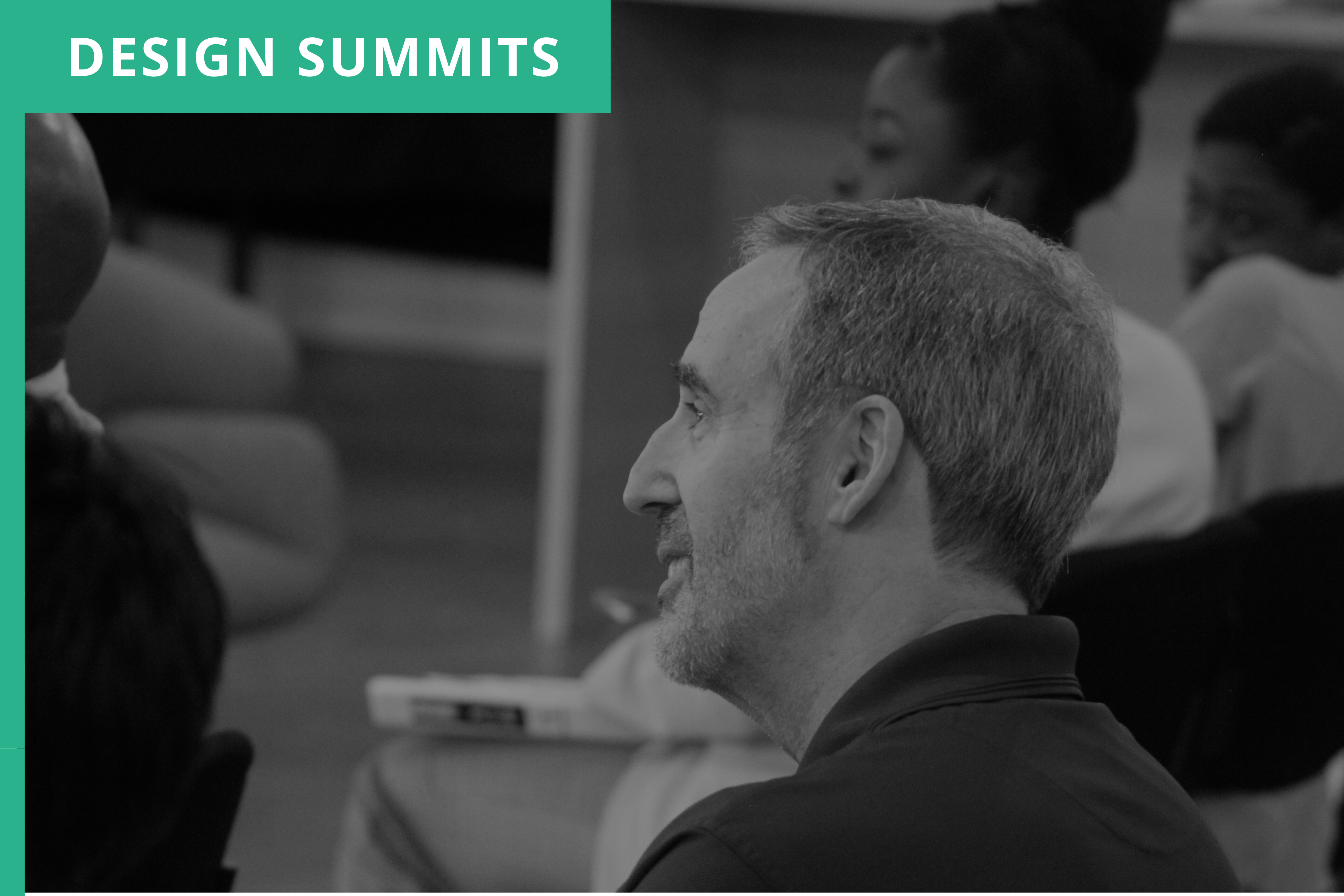 A man smiling while listening to a panelist at our accessibility and inclusive design meetup. A diverse group of attendees are visible in the background. Blue label in the left corner with the project title, Design Summits.