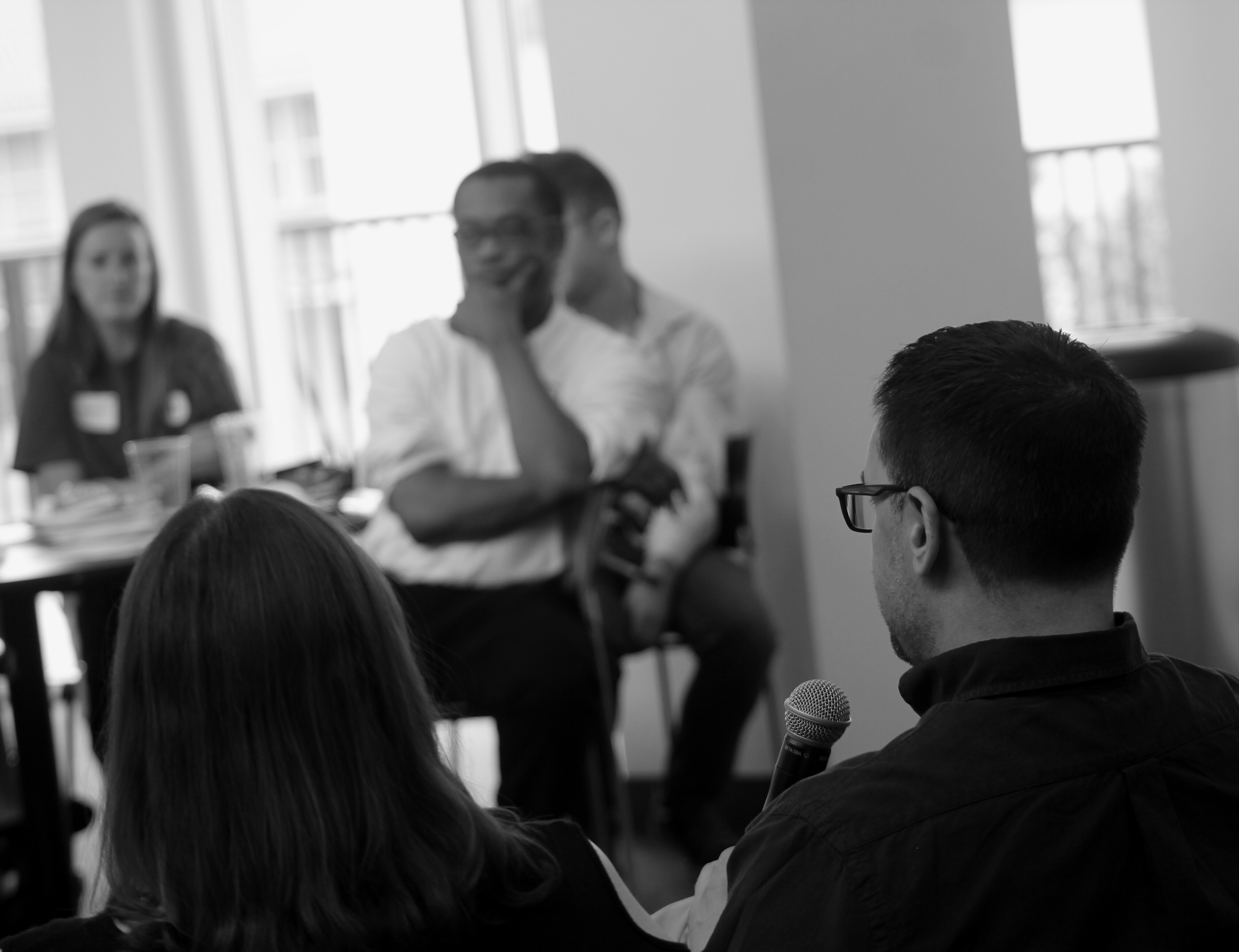 A hispanic man speaking to a diverse crowd with another panelist.