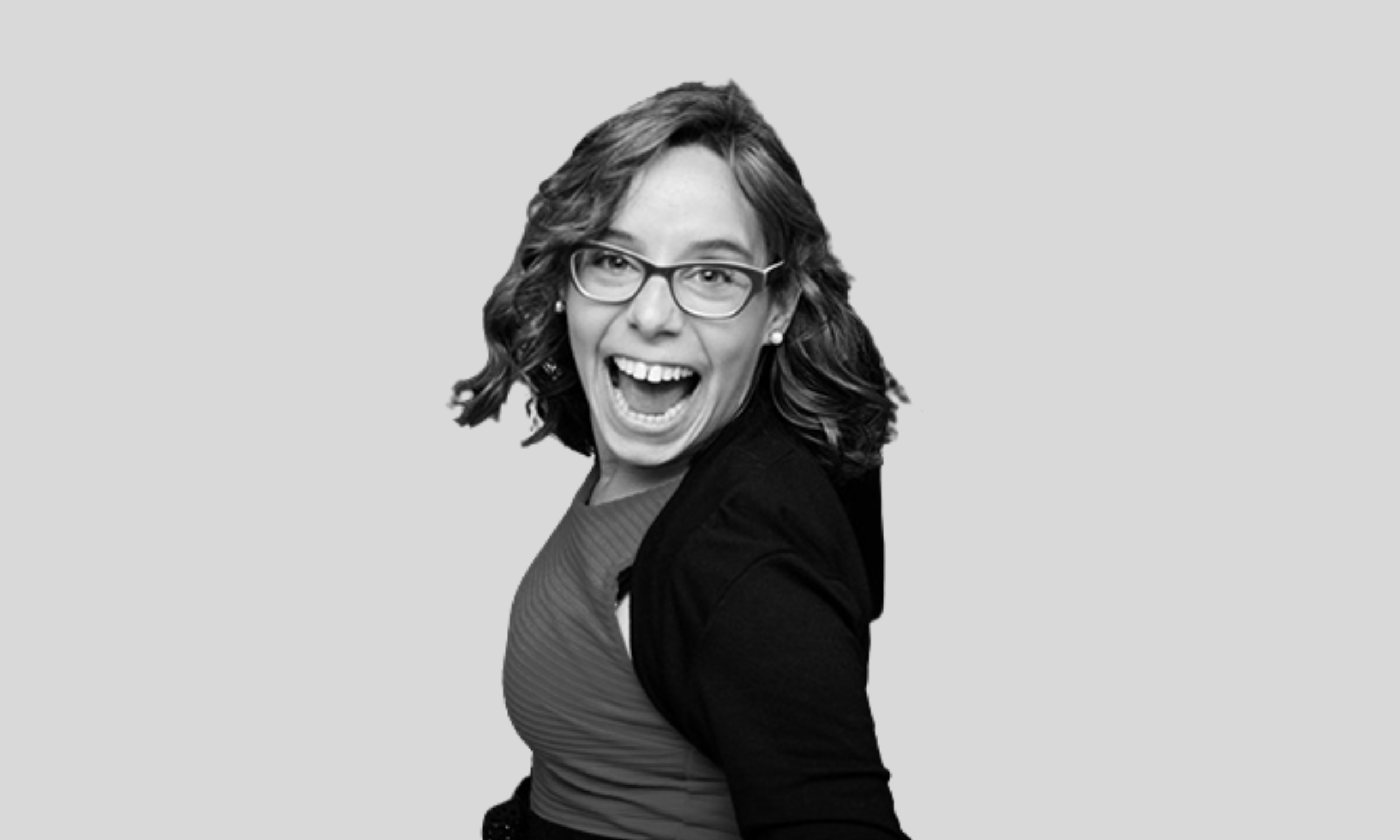 An Argentine woman faces the cameria and smiles widely. She has curly, chin-length brown hair and is wearing a black jacket and glasses.